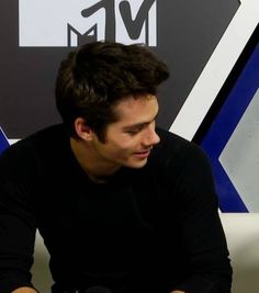 a man sitting on top of a white couch next to a microphone