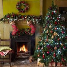 two christmas trees in front of a fire place