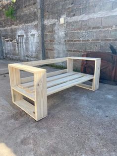 a wooden bench sitting on top of a cement floor next to a brick wall and potted planter