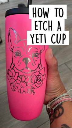 a person holding up a pink cup with a dog drawn on it's side