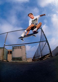 a man flying through the air while riding a skateboard in front of a fence