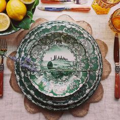 a table topped with plates and silverware next to lemons