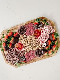 a wooden platter filled with chocolate covered strawberries and other fruit toppings on top of a white surface