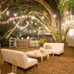 an outdoor seating area with lights strung from the trees