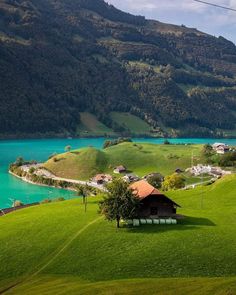 an aerial view of a green valley with blue water and mountains in the background,