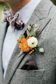 a man wearing a suit and tie with an orange flower on his lapel pin