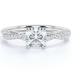 a white gold engagement ring with diamonds on the band and a round cut diamond in the center