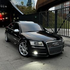 a black car parked in front of a fence