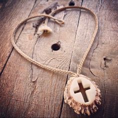 a wooden cross is hanging from a rope on a piece of drift wood with shells and seashells around it