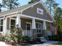 a small gray and white house with an american flag on the porch