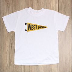 Represent West Point with this fresh and clean, vintage inspired pennant design. Details - 100% jersey polyester - Machine wash cold, tumble dry low - Colors on screen may vary slightly from actual item. Sketch + Sentiment is officially licensed with the United States Military Academy at West Point. White Collegiate Tops For School, Retro Cotton T-shirt With Name Print, White Team Spirit School T-shirt, White Team Spirit T-shirt For School, Cotton Shirt For Sports Events With School Spirit, Vintage White Top For School, Collegiate Cotton T-shirt With Name Print, Retro Cotton Tops With Team Name, Collegiate Cotton Pre-shrunk Shirt