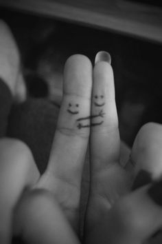 two fingers with smiley faces drawn on them, one holding the other's hand