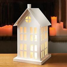 a lit house on a table with candles in the background