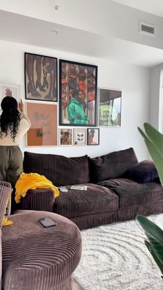 a woman is standing in the middle of a living room looking at pictures on the wall