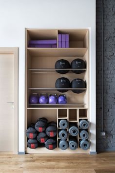 a wooden shelf filled with lots of dumbs and yoga mats on top of it