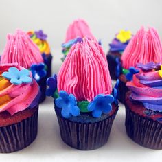 some cupcakes with pink frosting and colorful decorations