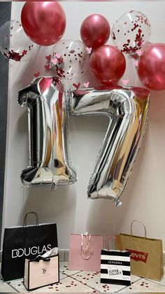 balloons and gift bags on a table in front of a wall with the number seventy