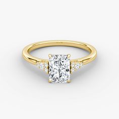 a yellow gold engagement ring with a princess cut diamond in the center and side stones