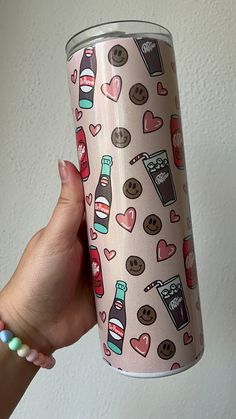 a woman's hand holding a pink coffee cup with hearts and cookies on it