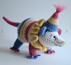 a small crocheted animal wearing a party hat and sweater with pink pompom hair