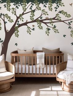 a baby's room with a crib and tree wall decal