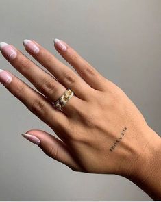 a woman's hand with a ring on her left wrist and tattoos on the middle finger