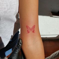 a woman's arm with a red butterfly tattoo on the left side of her arm