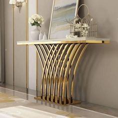 a gold console table with white flowers and pictures on the wall in front of it