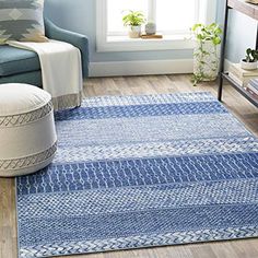 a living room with a blue rug on the floor next to a chair and window