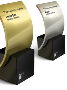 two shiny metal awards on black pedestals with gold and silver ribbons in each one