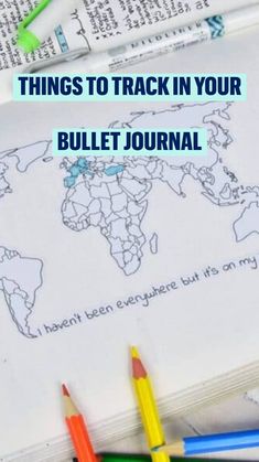 the world map is drawn on top of an open book with colored pencils next to it