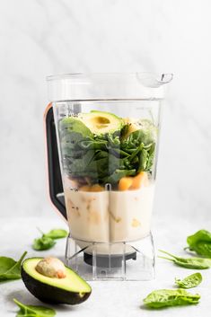 an avocado and spinach salad in a blender on a white surface