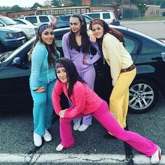 four young women posing in front of a car