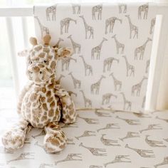 a stuffed giraffe sitting on top of a bed next to a wallpaper