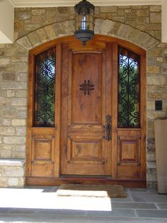 a large wooden door sitting inside of a stone building with two lights on each side