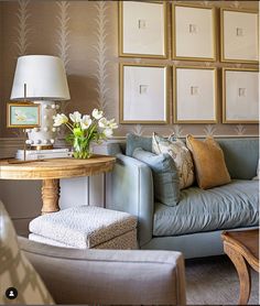 a living room filled with furniture and framed pictures on the wall above a coffee table