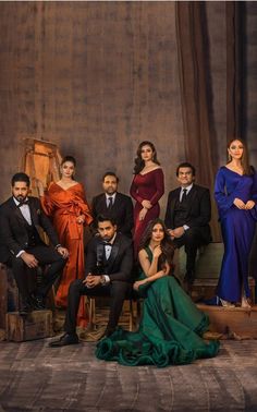 a group of people sitting next to each other in front of a wooden wall wearing suits and ties