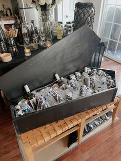 an open trunk filled with lots of bottles and glasses on top of a wooden table