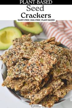 a bowl full of plant - based crackers with avocado and other fruit in the background