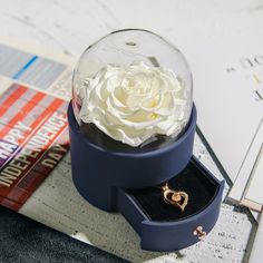 a pink rose in a blue box on top of a table