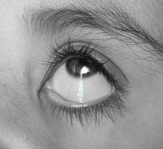 a close up of a person's eye with water dripping from the center of their iris