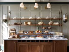 a counter with breads and pastries on it in a room that has wood paneling