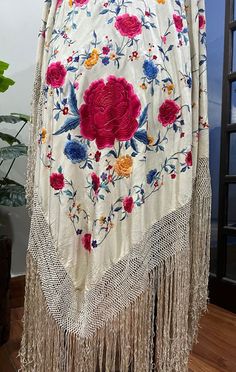 This antique white silk red roses floral embroidered Canton piano shawl dates from the 1920s.  It is made of an off white cream color silk fabric background, with colorful silk raised padded satin stitch hand embroidery work. There are embroidered red roses in each corner and a variety of vine leaf flowers. There is a fabulous hand knotted macramé off white silk fringe measuring 25 inches long surrounding the entire shawl with rounded corners. The shawls fabric square measures 65 by 65 inches. T Vintage White Shawl Scarf, Embroidered Beige Pashmina Shawl, Edgy Clothes, Cream Color Background, Piano Shawl, Cultural Traditions, Fabric Background, Fringe Shawl, Color Background