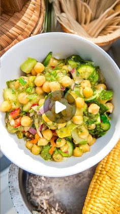 a white bowl filled with vegetables next to corn