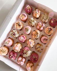 a box filled with lots of pink and white cupcakes