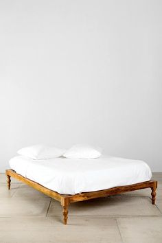 a bed sitting on top of a hard wood floor next to a white painted wall