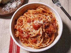 a white bowl filled with pasta and sauce on top of a table next to bread