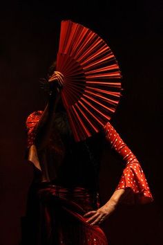 a woman holding an umbrella while standing in front of a black background with polka dots