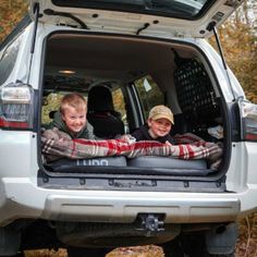 two boys sitting in the back of a vehicle