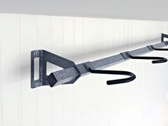 a pair of scissors hanging from the side of a hook on a wall with hooks attached to it